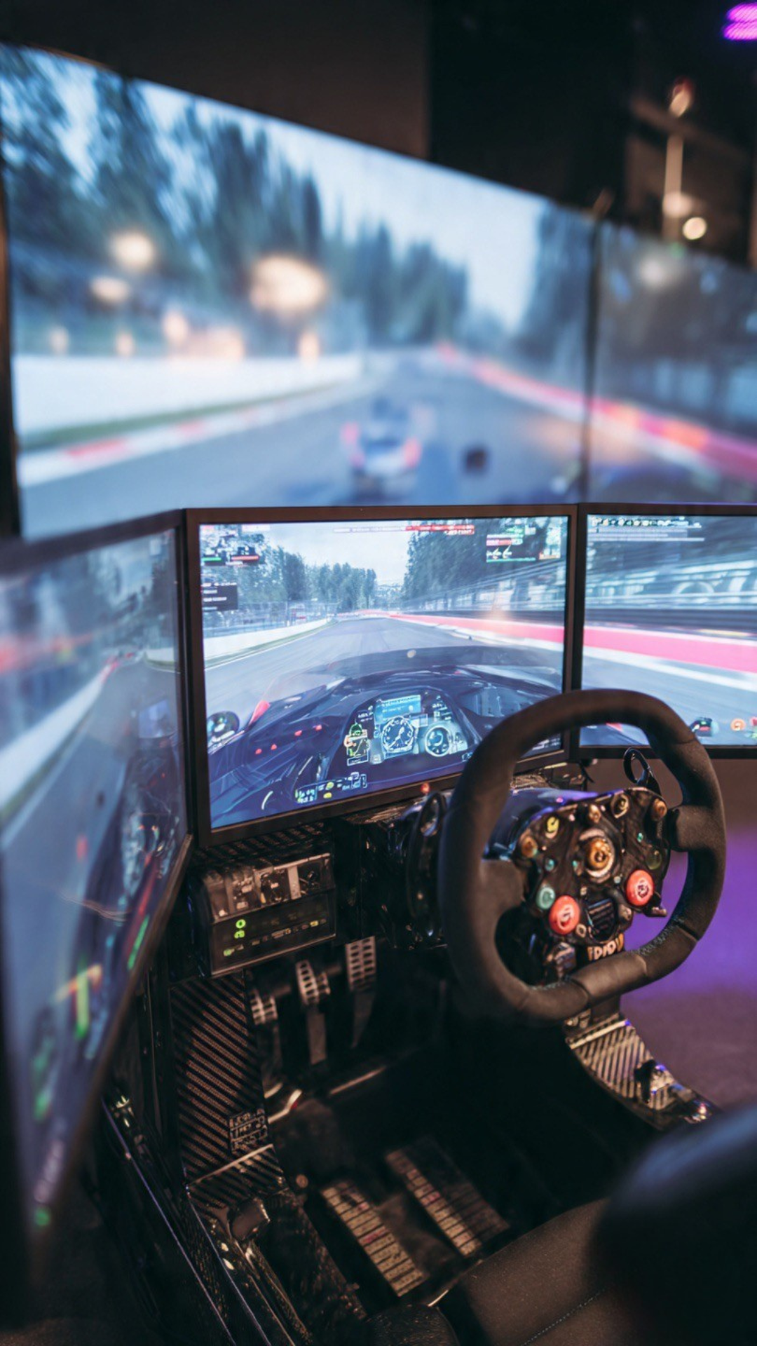 Primer plano de volante estilo Fórmula 1 en un simulador con sistema de triple pantalla